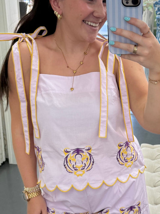 Woman taking a mirror selfie wearing a white dress with gold accents in a room.