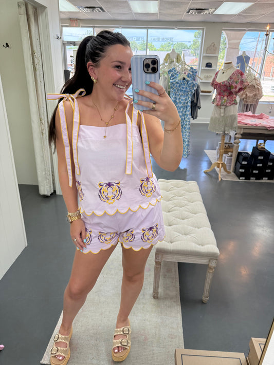 Woman taking a mirror selfie wearing a white dress with gold accents in a room.
